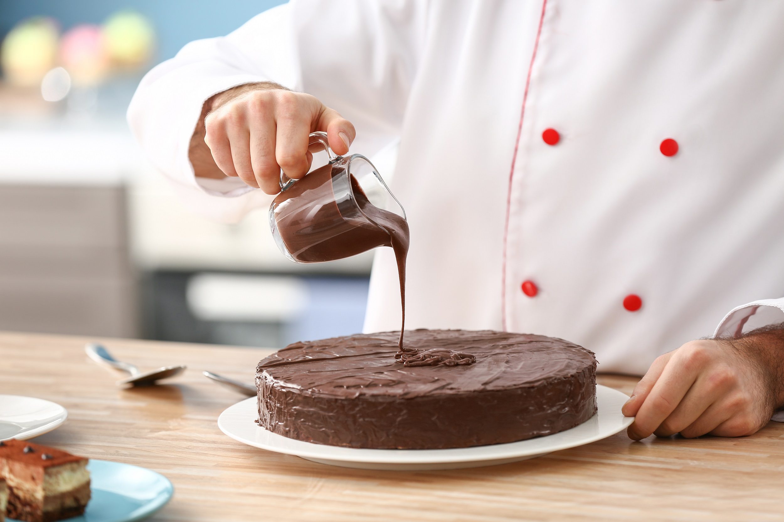 Male confectioner decorating tasty chocolate cake in kitchen, cl